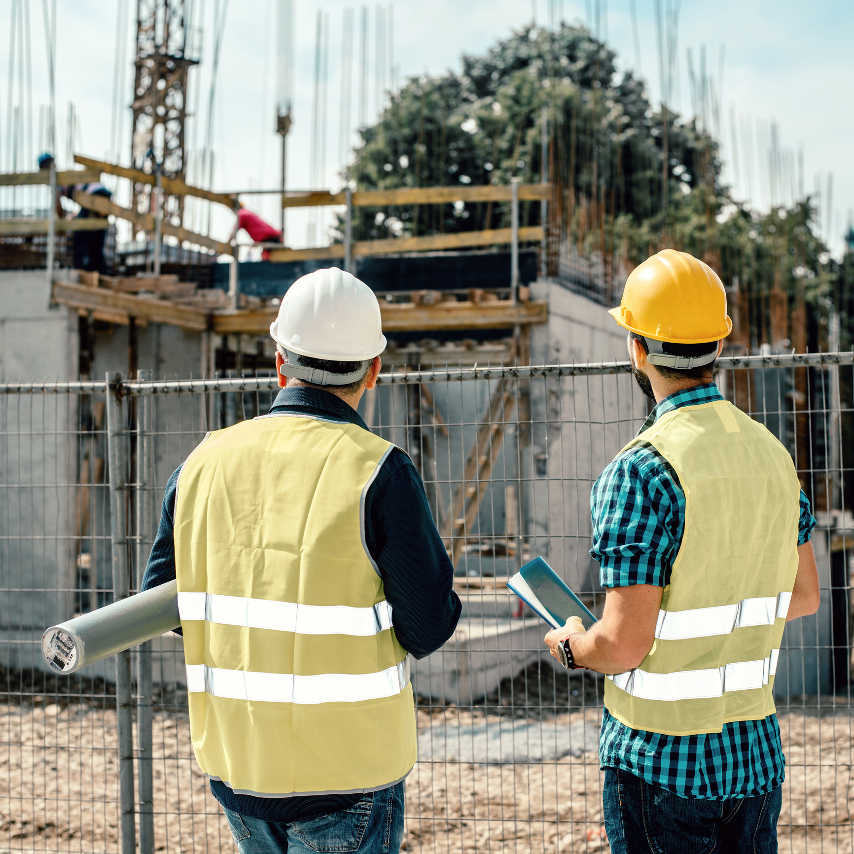 Two workers inspecting construction progress outdoors.