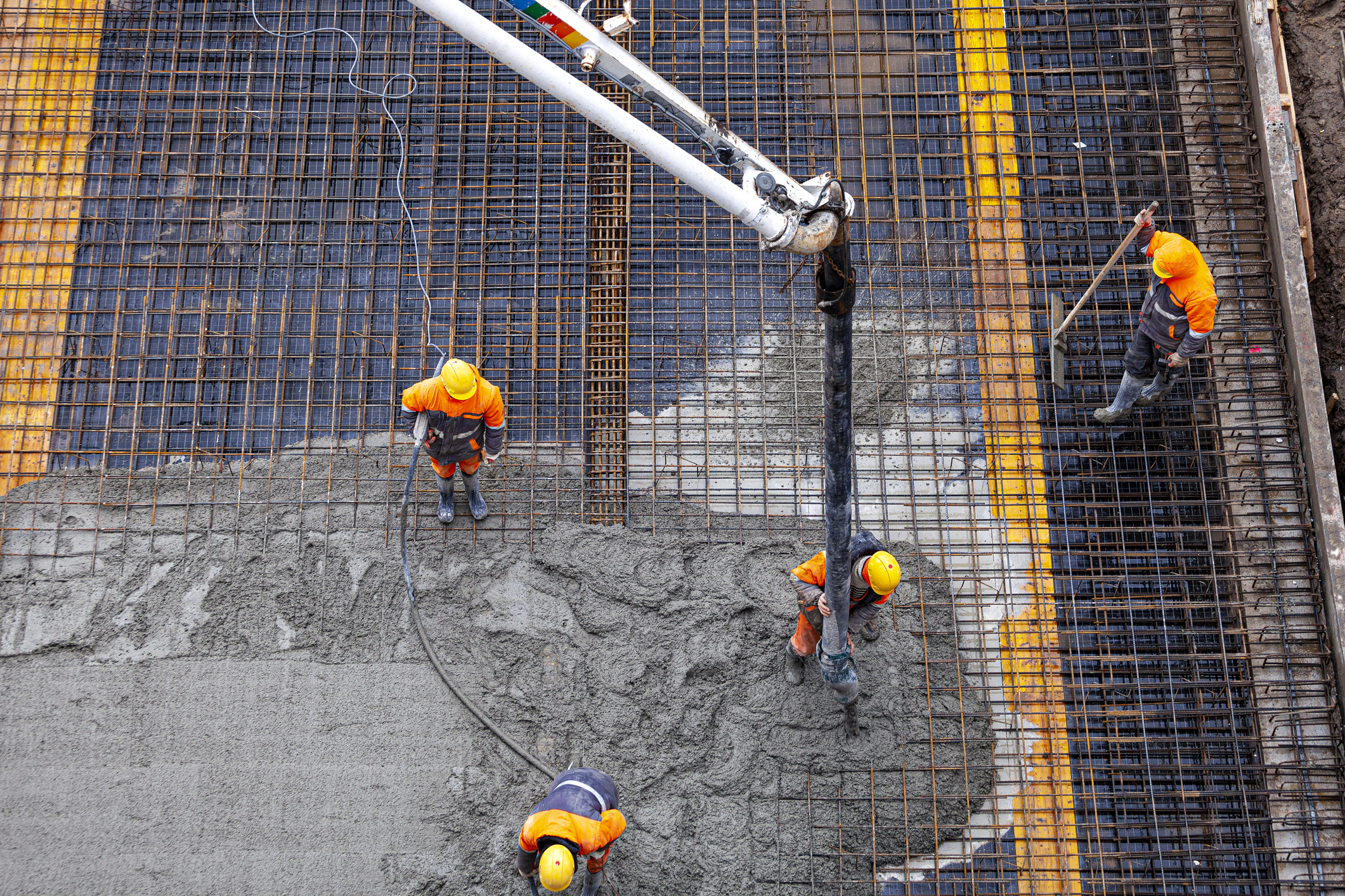 Construction workers pouring concrete on rebar