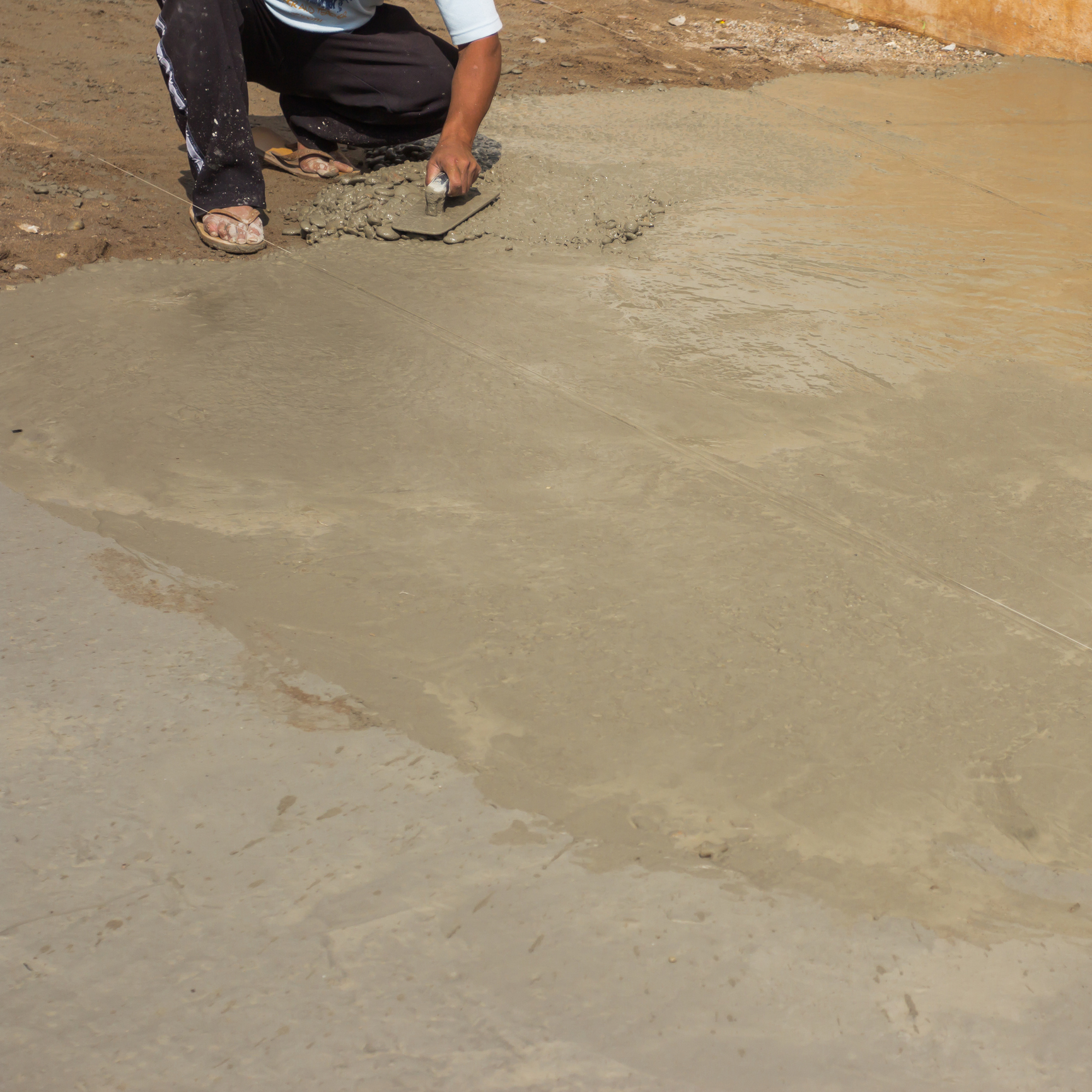 Person applying concrete on ground