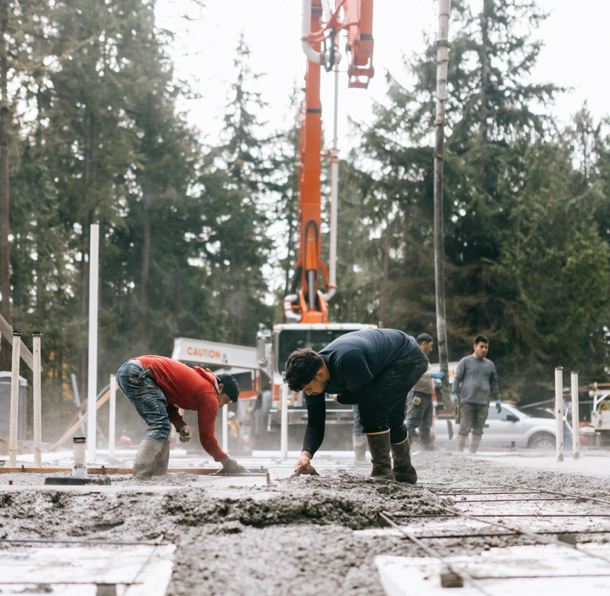 Workers smoothing concrete on construction site.